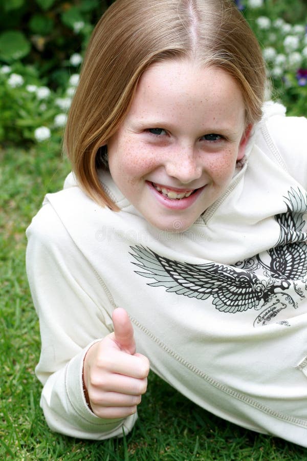 A white caucasian girl child showing thumbs up in the garden with a happy expression on her face. A white caucasian girl child showing thumbs up in the garden with a happy expression on her face