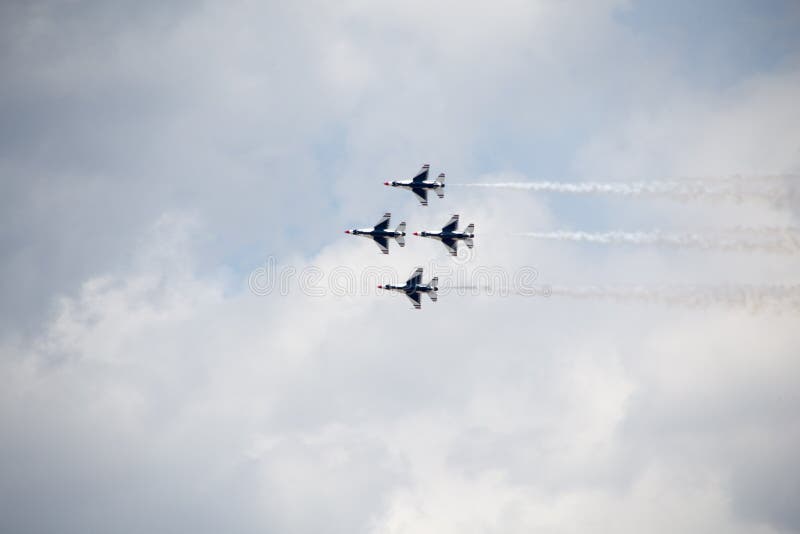 The underside of four USAF Thunderbirds against a cloudy sky, trailing smoke. The underside of four USAF Thunderbirds against a cloudy sky, trailing smoke.