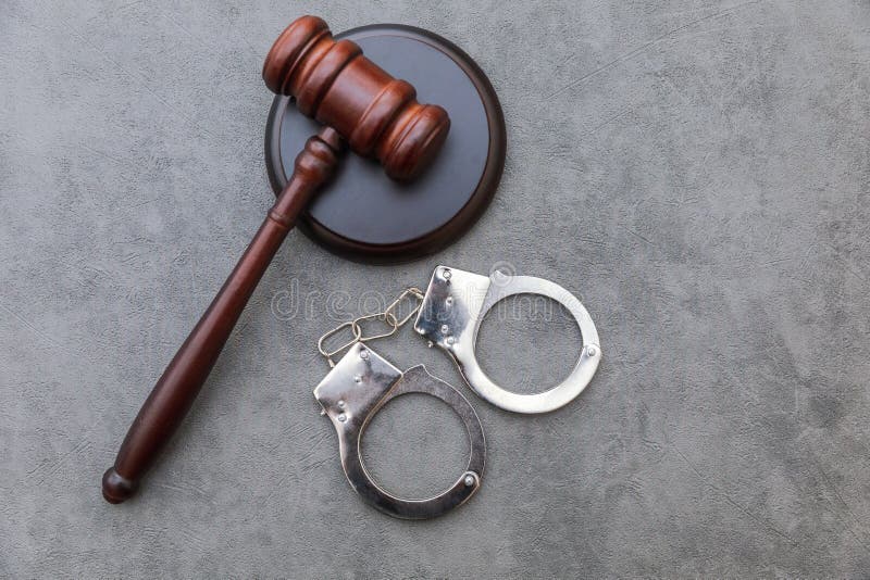 Thème du droit. procès devant la cour de justice en session. menottes du juge gavel sur une table grise dans un bureau d'avocat ou une session du tribunal. mailet du juge sur le fond gris pierre béton. justice et droits de l'homme