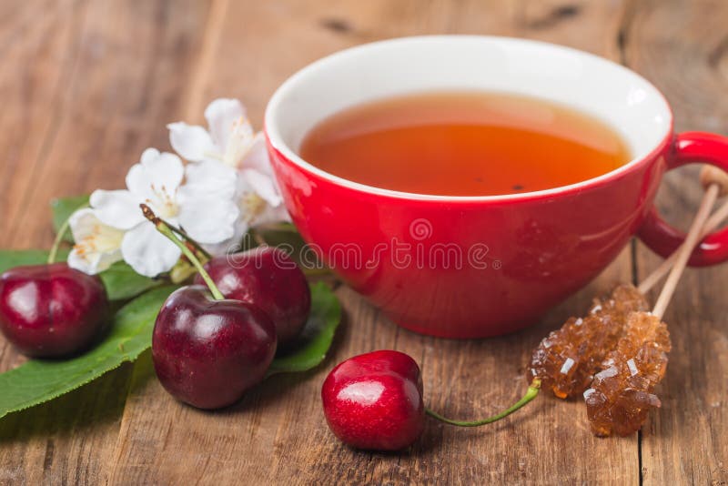 Thé de l'anglais noir dans la tasse rouge avec la cerise image stock Thé de l'anglais noir dans la tasse rouge avec la cerise image stock