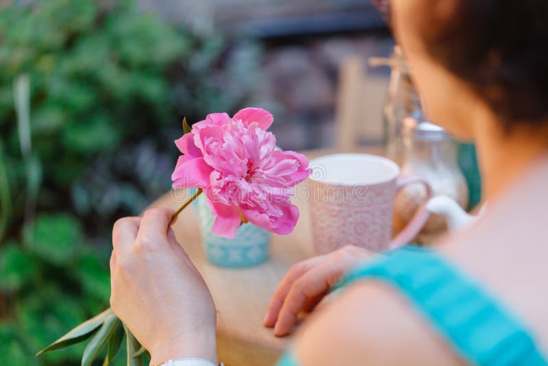 Thé potable se reposant de femme à un café avec la fleur à disposition photo libre de droits Thé potable se reposant de femme à un café avec la fleur à disposition photo libre de droits