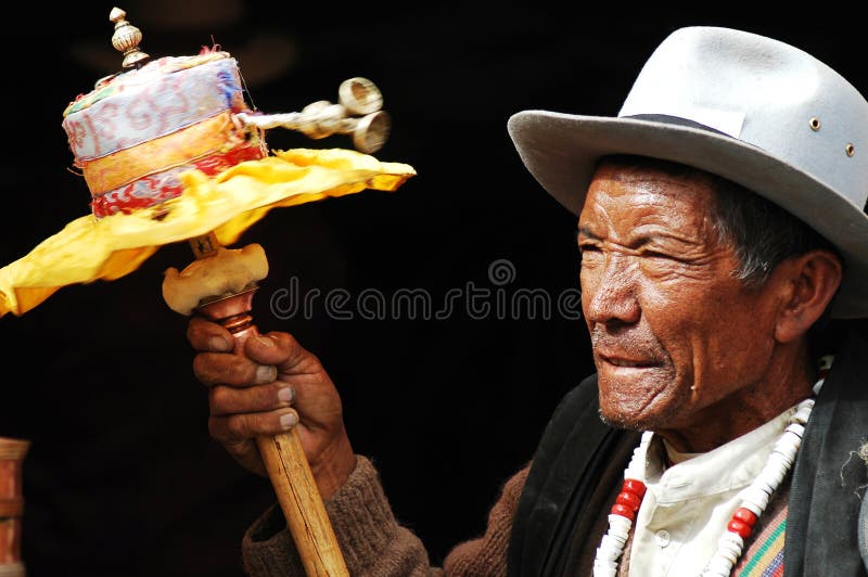 Portrait of a Tibetan man holding a prayer wheel in hand isolated on a black background.Used for news and articles about the people and religion in Tibet. Portrait of a Tibetan man holding a prayer wheel in hand isolated on a black background.Used for news and articles about the people and religion in Tibet.