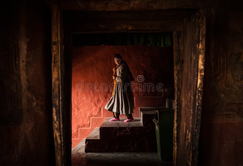 Thikse Monastery in Ladakh, India - AUGUST 20: Tibetan monk woman goes down the stairs in Thiksey Monastery on August 20, 2016 in Thiksey village in Ladakh, India. Thikse Monastery in Ladakh, India - AUGUST 20: Tibetan monk woman goes down the stairs in Thiksey Monastery on August 20, 2016 in Thiksey village in Ladakh, India