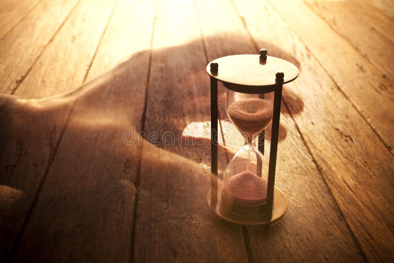 An image that explores the aspects of time with a hand and hourglass. An image that explores the aspects of time with a hand and hourglass