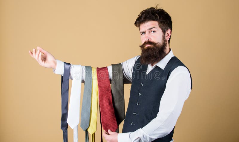 This tie is a must have. Brutal hipster holding colorful tie collection. Bearded man choosing neck tie. Find yourself a unique tie and mens accessories.