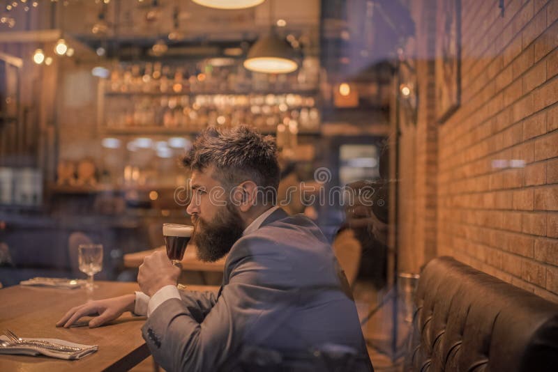 Tiempo de la cerveza Hombre de negocios con la bebida larga de la barba en club del cigarro el cliente serio de la barra se sient imagen de archivo libre de regalías Tiempo de la cerveza Hombre de negocios con la bebida larga de la barba en club del cigarro el cliente serio de la barra se sient imagen de archivo libre de regalías