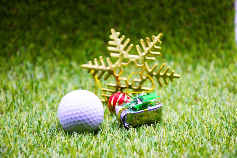 Golf ball and Xmas ornament are on green grass. Golf ball and Xmas ornament are on green grass