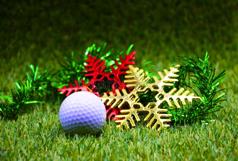 Golf ball and Xmas ornament are on green grass. Golf ball and Xmas ornament are on green grass