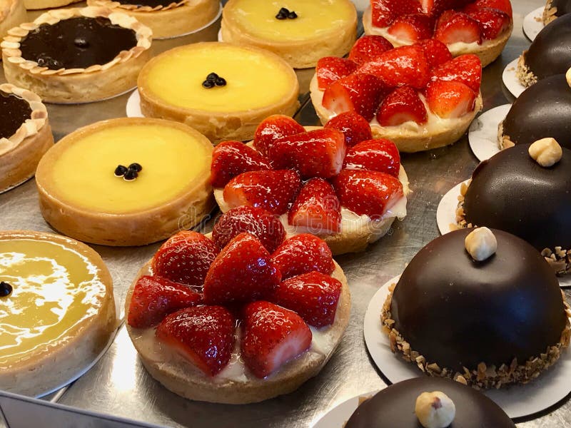 Tienda de pasteles con la variedad de tartas, tortas, nata quemada, con la fresa, el chocolate, el limón, las peras y las rebanad foto de archivo Tienda de pasteles con la variedad de tartas, tortas, nata quemada, con la fresa, el chocolate, el limón, las peras y las rebanad foto de archivo