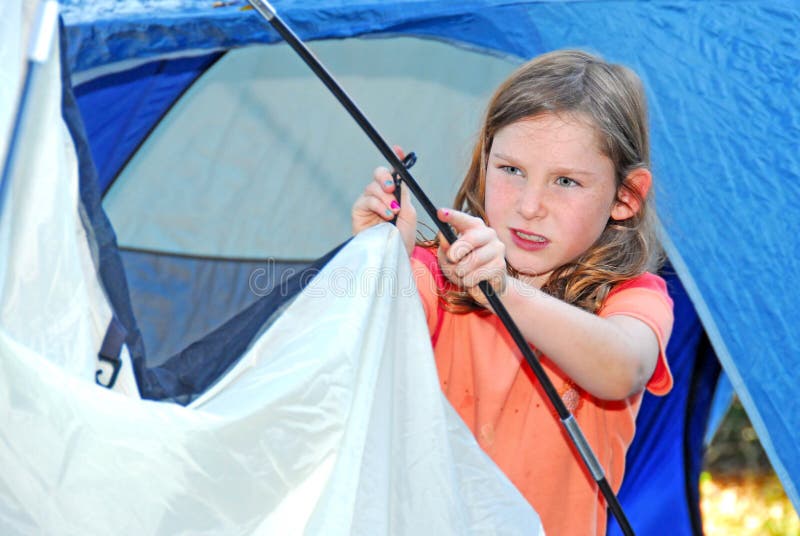 Young girl out camping learning how to pitch tent. Young girl out camping learning how to pitch tent