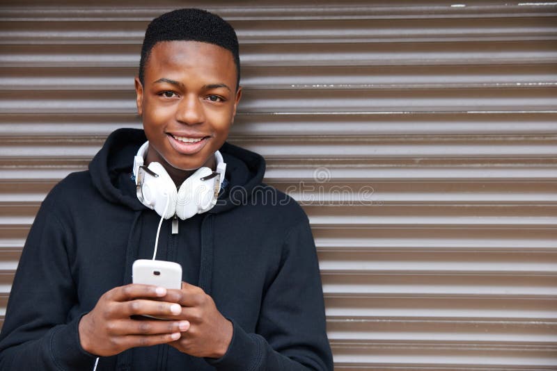 Tiener die aan Muziek luisteren en Telefoon in het Stedelijke Plaatsen met behulp van royalty-vrije stock foto Tiener die aan Muziek luisteren en Telefoon in het Stedelijke Plaatsen met behulp van royalty-vrije stock foto