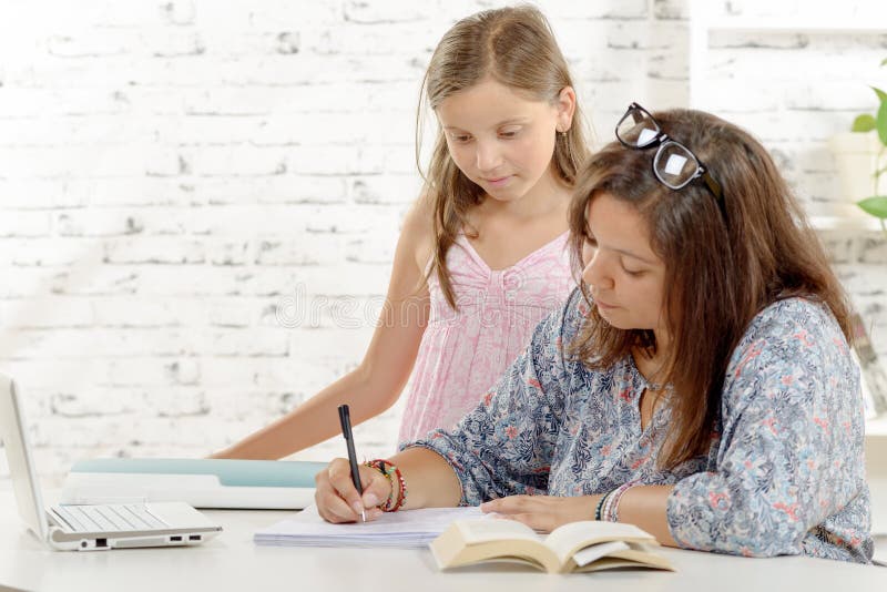 Tiener die haar thuiswerk met haar doen weinig zuster stock afbeelding Tiener die haar thuiswerk met haar doen weinig zuster stock afbeelding