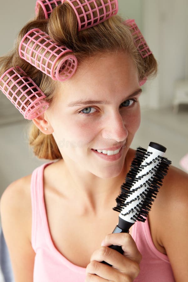 Teenage girl using curlers in her hair and smiling. Teenage girl using curlers in her hair and smiling