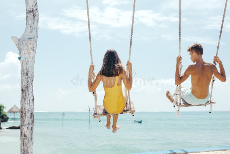 Tiener en jongens het hangen op schommeling met een overzeese mening in strandkoffie royalty-vrije stock foto's Tiener en jongens het hangen op schommeling met een overzeese mening in strandkoffie royalty-vrije stock foto's