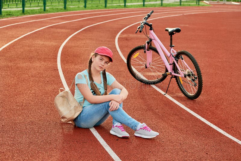 Tiener het ontspannen op een stadion De tiener ontspant met de fiets royalty-vrije stock foto Tiener het ontspannen op een stadion De tiener ontspant met de fiets royalty-vrije stock foto