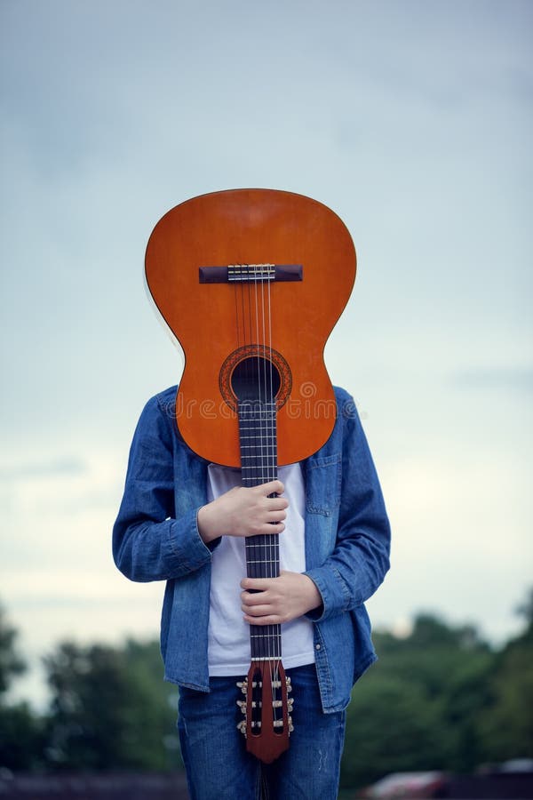 Tiener met een gitaar in plaats van een hoofd in het park Gekke en koele jonge mens met een gitaar royalty-vrije stock fotografie Tiener met een gitaar in plaats van een hoofd in het park Gekke en koele jonge mens met een gitaar royalty-vrije stock fotografie