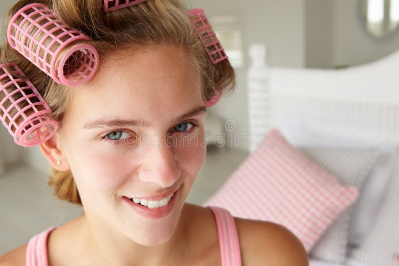 Teenage girl with hair in pink curlers smiling at camera. Teenage girl with hair in pink curlers smiling at camera
