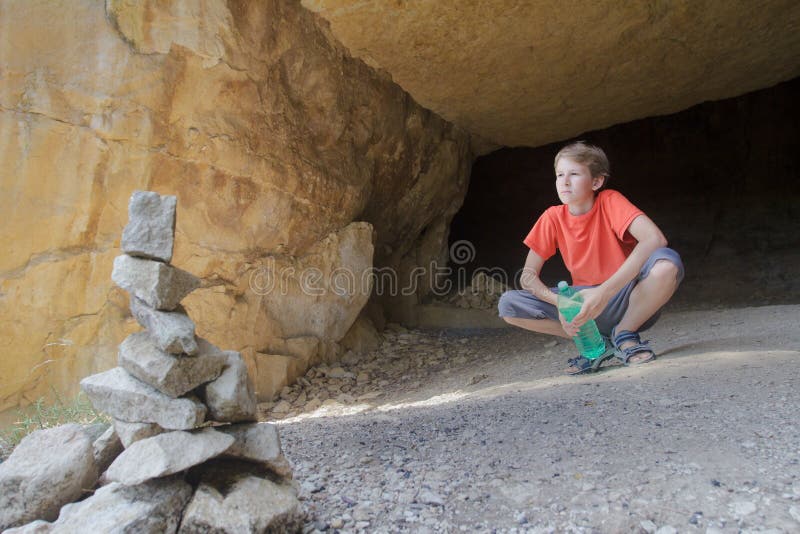 Tienerjong geitje die bergmening bekijken van rotshol met steensteenhoop bij voorgrond stock afbeeldingen Tienerjong geitje die bergmening bekijken van rotshol met steensteenhoop bij voorgrond stock afbeeldingen
