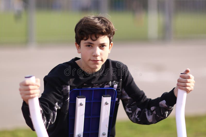 Tienerjongen de bicepsen van het opleidingswapen in openluchtgymnastiek in de foto van het stadspark dicht omhoog stock foto's Tienerjongen de bicepsen van het opleidingswapen in openluchtgymnastiek in de foto van het stadspark dicht omhoog stock foto's