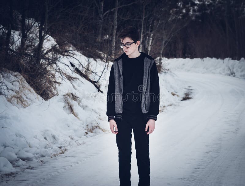 Tienerjongen die zich op een Snow-Covered Weg bevinden royalty-vrije stock afbeelding Tienerjongen die zich op een Snow-Covered Weg bevinden royalty-vrije stock afbeelding