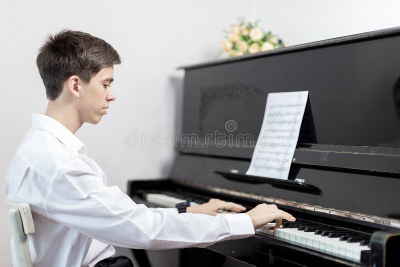 Teenage boys play piano in class or at home . student learn to play the piano. Teenage boys play piano in class or at home . student learn to play the piano