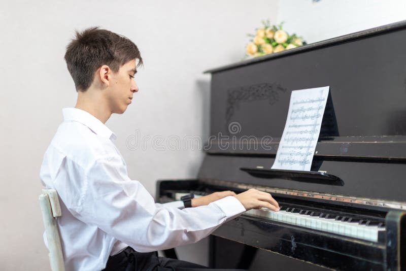 Teenage boys play piano in class or at home . student learn to play the piano. Teenage boys play piano in class or at home . student learn to play the piano