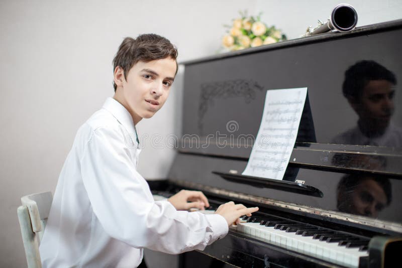 Teenage boys play piano in class or at home . student learn to play the piano. Teenage boys play piano in class or at home . student learn to play the piano