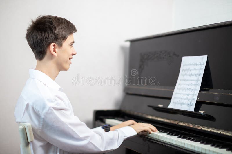 Teenage boys play piano in class or at home . student learn to play the piano. Teenage boys play piano in class or at home . student learn to play the piano