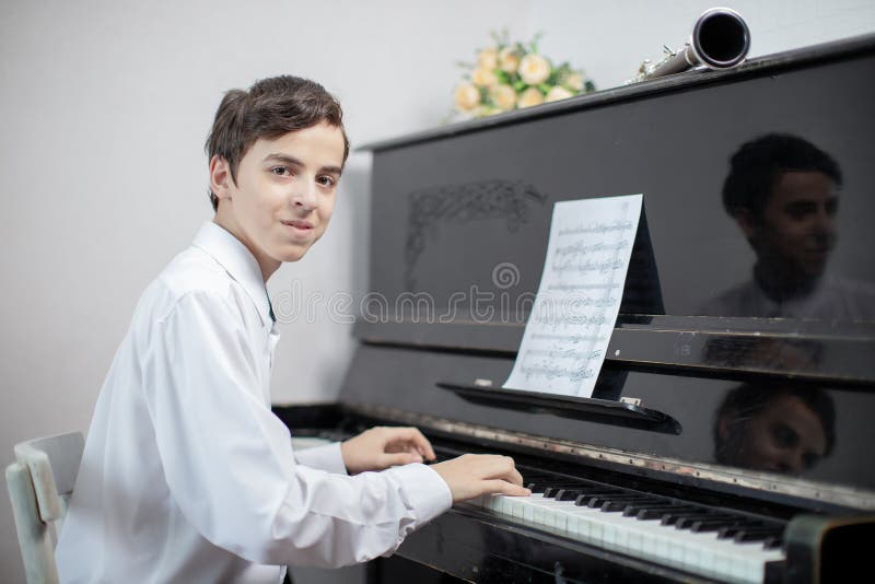 Teenage boys play piano in class or at home . student learn to play the piano. Teenage boys play piano in class or at home . student learn to play the piano