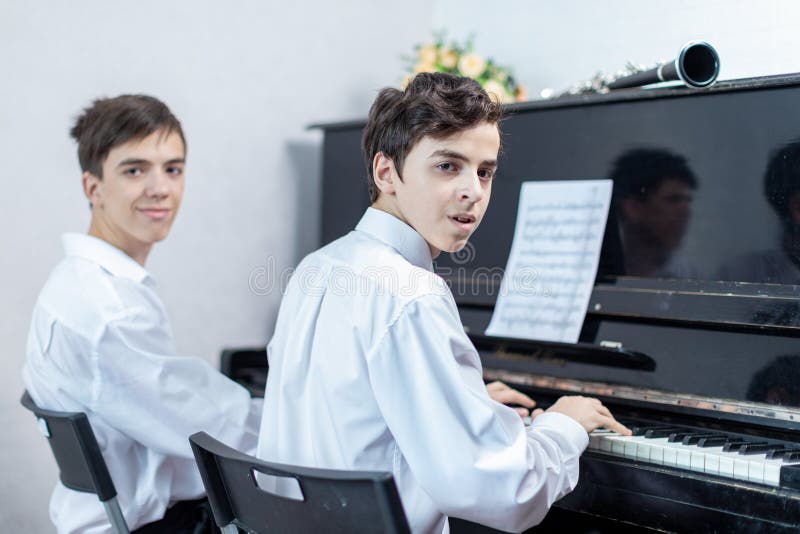 Teenage boys play piano in class or at home . student learn to play the piano. Teenage boys play piano in class or at home . student learn to play the piano