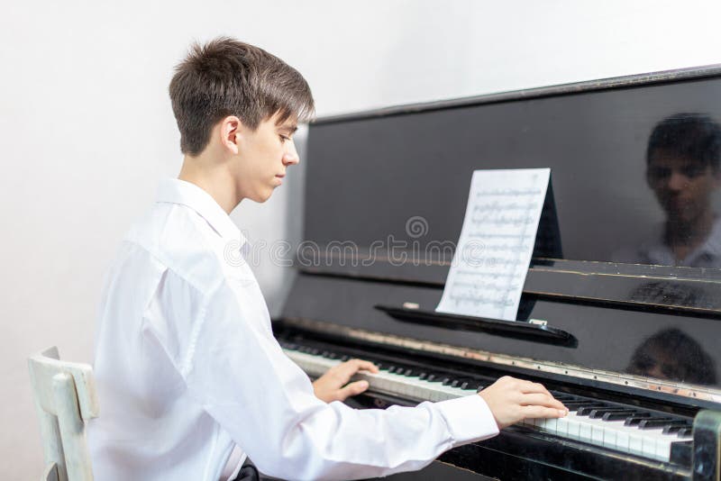 Teenage boys play piano in class or at home . students learn to play the piano. Teenage boys play piano in class or at home . students learn to play the piano