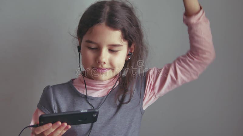 Tienermeisje die aan muziek op hoofdtelefoons luisteren en op een smartphone dansen royalty-vrije stock afbeelding Tienermeisje die aan muziek op hoofdtelefoons luisteren en op een smartphone dansen royalty-vrije stock afbeelding
