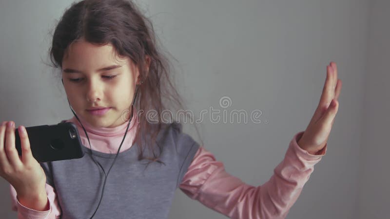 Tienermeisje die aan muziekhoofdtelefoons luisteren en op een smartphone dansen royalty-vrije stock afbeelding Tienermeisje die aan muziekhoofdtelefoons luisteren en op een smartphone dansen royalty-vrije stock afbeelding