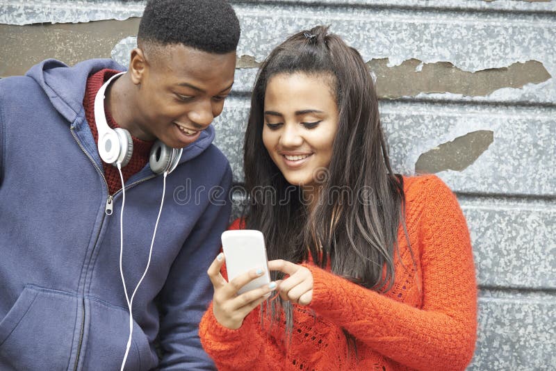 Tienerpaar die Tekstbericht op Mobiele Telefoon delen stock afbeeldingen Tienerpaar die Tekstbericht op Mobiele Telefoon delen stock afbeeldingen
