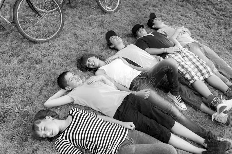 Tieners en meisjes die op de lenteweide liggen na fietsrit royalty-vrije stock foto Tieners en meisjes die op de lenteweide liggen na fietsrit royalty-vrije stock foto