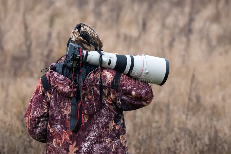 Tierphotograph Fotojäger Ein Mann in der Tarnungs-Uniform mit einer schwarzen Kamera und einer großen weißen Linse Ein Mann mit e lizenzfreie stockfotos Tierphotograph Fotojäger Ein Mann in der Tarnungs-Uniform mit einer schwarzen Kamera und einer großen weißen Linse Ein Mann mit e lizenzfreie stockfotos