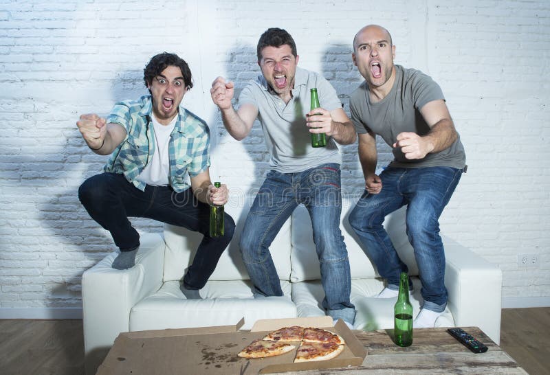 Tifosi fanatici degli amici che guardano gioco sulla TV che celebra scopo che grida felice pazzo immagine stock Tifosi fanatici degli amici che guardano gioco sulla TV che celebra scopo che grida felice pazzo immagine stock