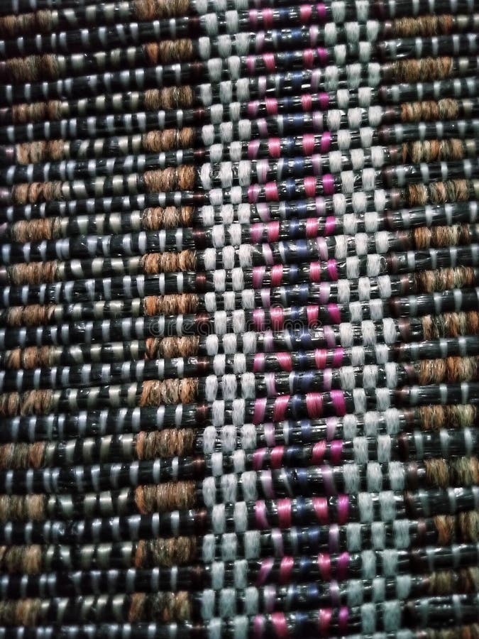A tight, detailed shot of a woven textile, showcasing a pattern of black, white, brown, and hints of pink and blue threads stock photo