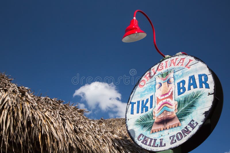 Ft. Pierce, USA - Febrary 24, 2013: The eye catching sign for the tiki bar is complimented by the thatched roof of the open air bar. Weekend festivities in the marina parking lot are regular event during the winter season. Tourist and locals alike enjoy spending time at the waterfront businesses, including the Tiki Bar. Ft. Pierce, USA - Febrary 24, 2013: The eye catching sign for the tiki bar is complimented by the thatched roof of the open air bar. Weekend festivities in the marina parking lot are regular event during the winter season. Tourist and locals alike enjoy spending time at the waterfront businesses, including the Tiki Bar.