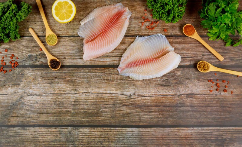 Tilapia de pescado fresco sobre mesa de madera con limón y condimento fotografía de archivo libre de regalías