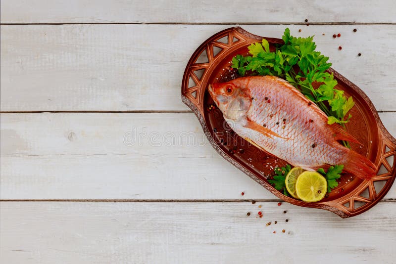Tilapia roja cruda con hierbas y limón y lima sobre fondo de madera. espacio de copia de vista superior imágenes de archivo libres de regalías