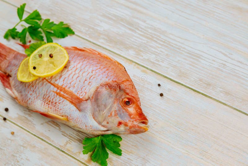 Tilapia roja cruda con hierbas y limón sobre fondo de madera. vista superior imagen de archivo libre de regalías