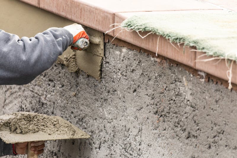 Tile Worker Applying Cement with Trowel at Pool Construction Site Stock