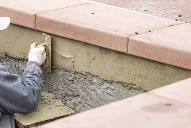 Tile Worker Applying Cement with Trowel at Pool Construction Site Stock