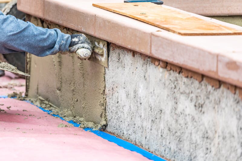 Tile Worker Applying Cement with Trowel at Pool Construction Site Stock