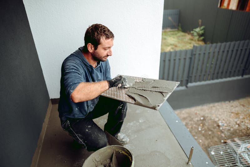 Tiler Placing Ceramic Wall Tile in Position Over Adhesive with Lash