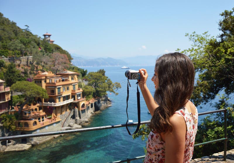 Tillbaka sida av den unga kvinnan som tar bilden av den härliga italienska fjärden i Portofino, lyckligt lopp till Europa, begrep fotografering för bildbyråer