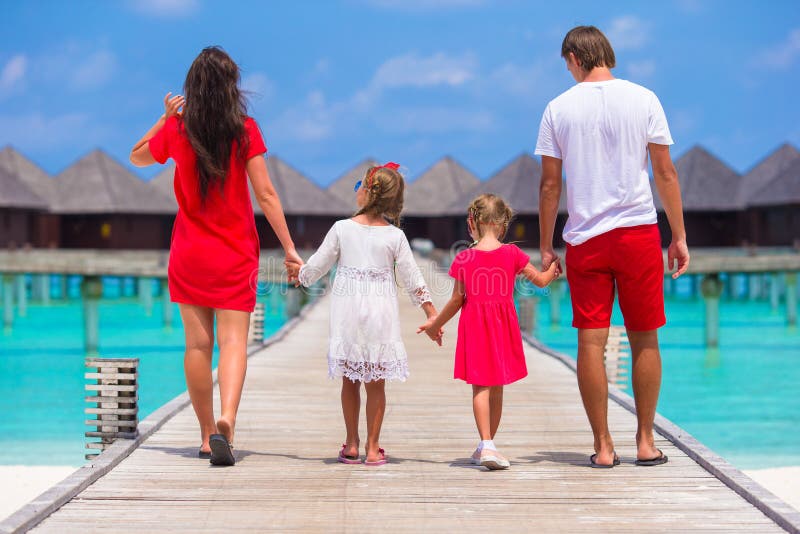 Tillbaka sikt av den härliga familjen på träbryggan royaltyfri bild Tillbaka sikt av den härliga familjen på träbryggan royaltyfri bild