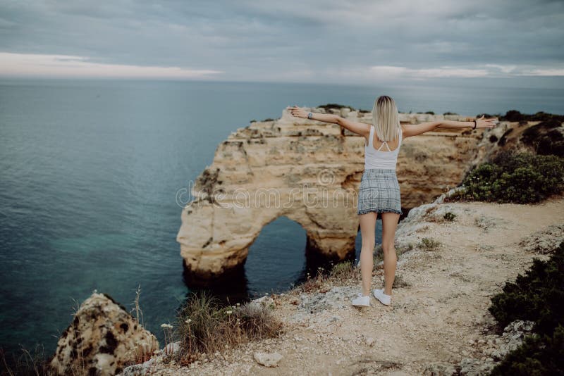 tillbaka sikt En turist för ung kvinna tycker om de härliga sikterna av Atlanticet Ocean och landskapet av kusten i port arkivfoto tillbaka sikt En turist för ung kvinna tycker om de härliga sikterna av Atlanticet Ocean och landskapet av kusten i port arkivfoto