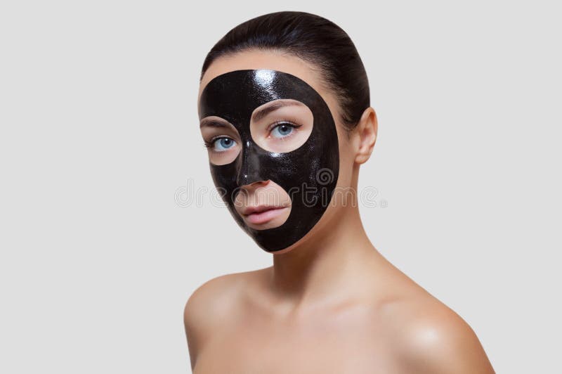 Tillvägagångssättet för att applicera en svart maskering till framsidan av en härlig kvinna fotografering för bildbyråer Tillvägagångssättet för att applicera en svart maskering till framsidan av en härlig kvinna fotografering för bildbyråer